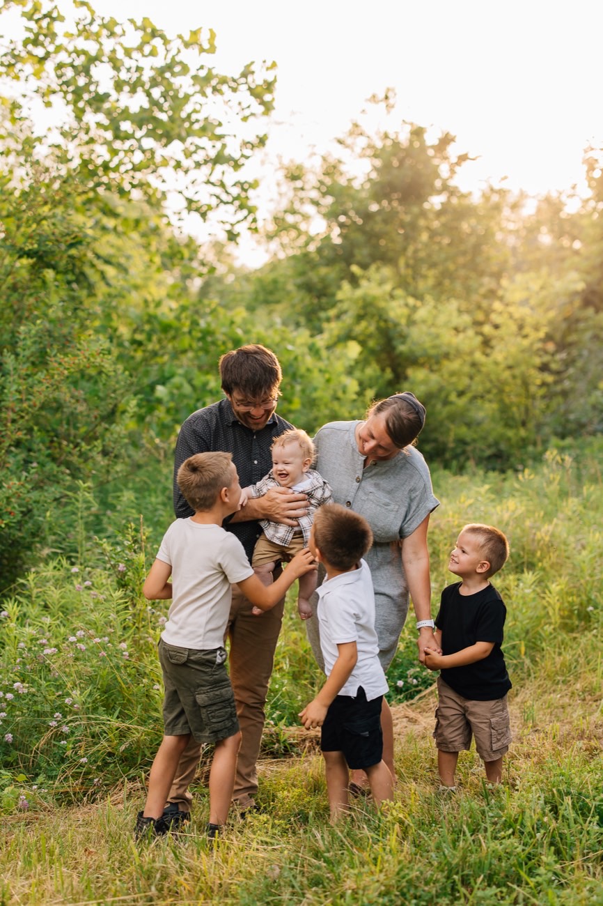 The owners and their four boys in a sunlit field at golden hour