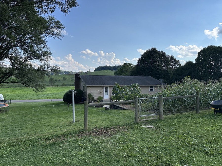 Rear of the home, with fenced gardens and hills beyond